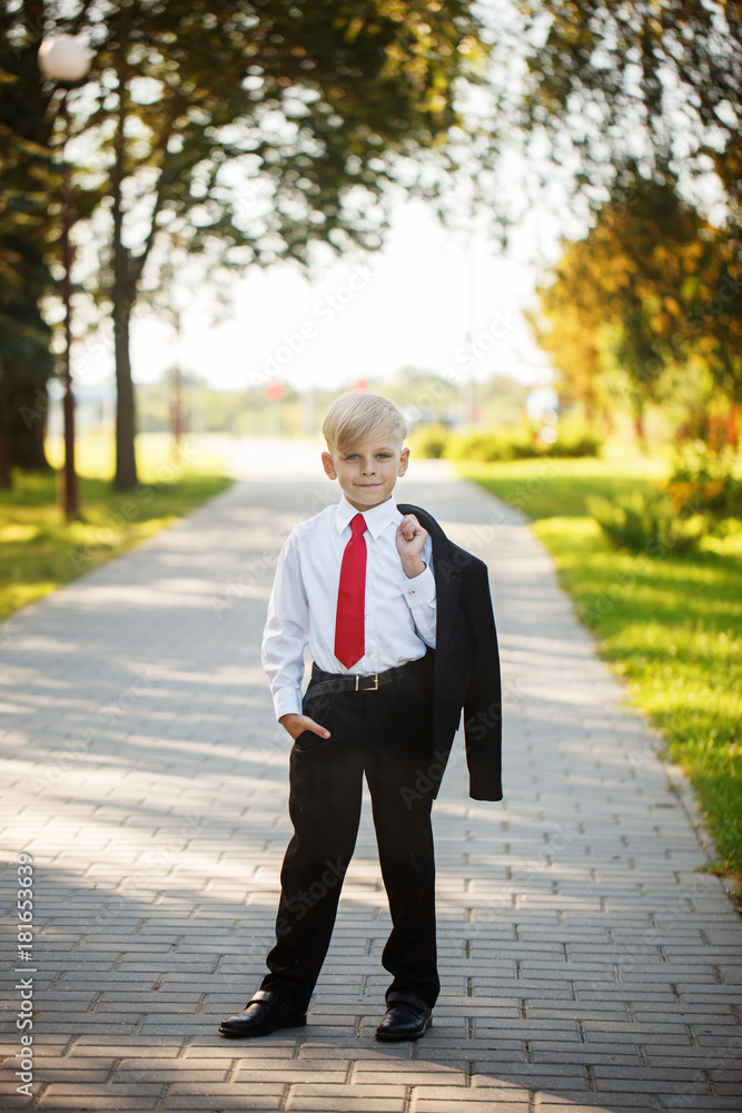 Little boy wearing business suit and red tie on nature background Little boy wearing business suit and red tie on nature background