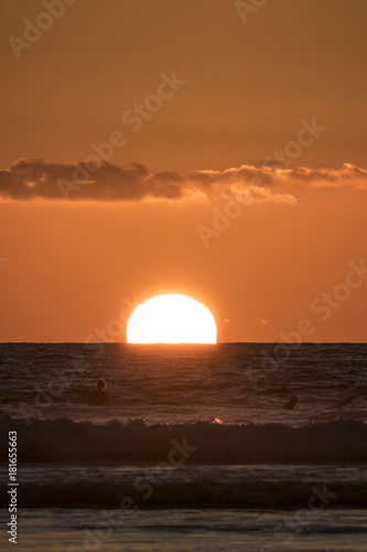 Fototapeta Naklejka Na Ścianę i Meble -  Sun setting on Surfers in the water