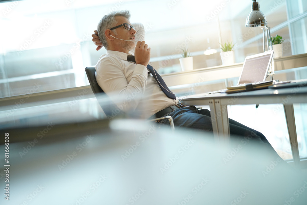 Businessman talking on phone in office, relaxing in chair Businessman talking on phone in office, relaxing in chair