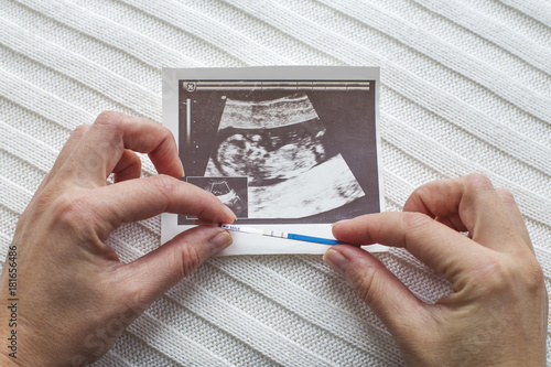Women's hands with a pregnancy test and ultrasound photo