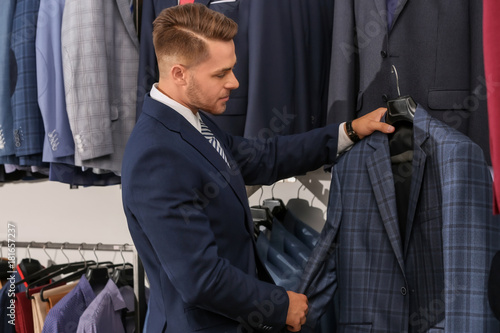 Young man choosing suit in ...