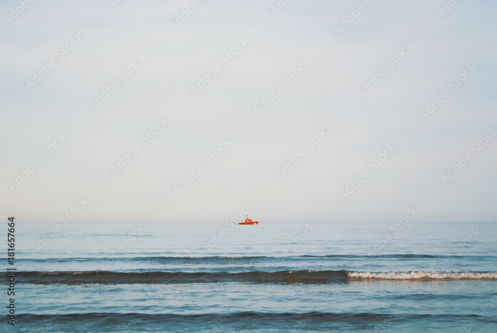 A view to Mediterranean sea and a red ship from a beach of Valencia in the evening, Spain.