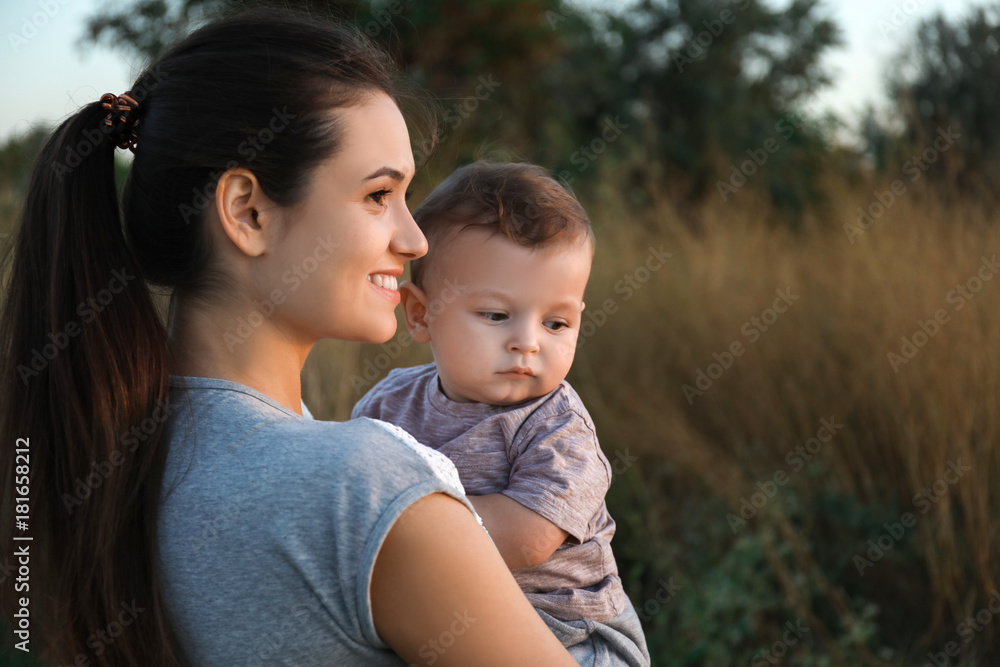 Beautiful young mother holding cute baby boy, outdoors Beautiful young mother holding cute baby boy, outdoors