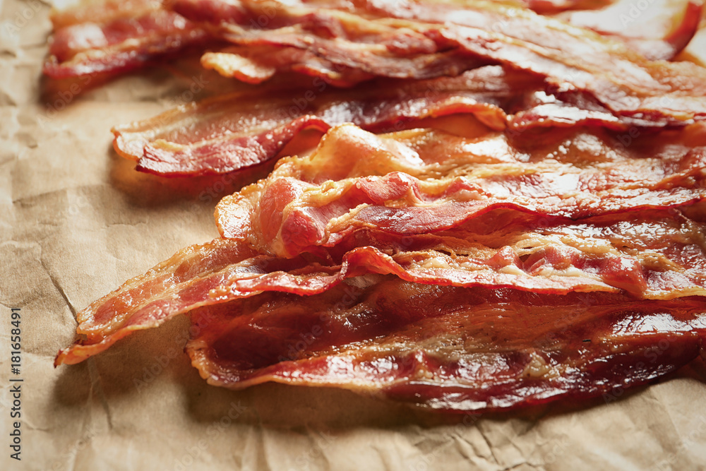 Obraz premium Cooked bacon rashers on parchment, closeup