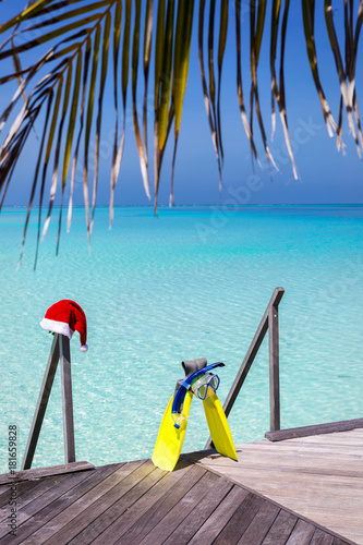 Urlaubskonzept: Schnorchelausrüstung mit Weihnachtsmütze vor türkisem Wasser der Malediven