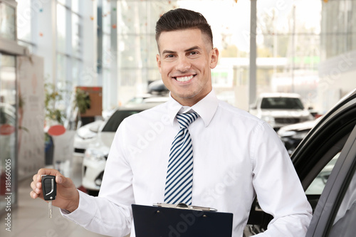 Salesman with key in car salon