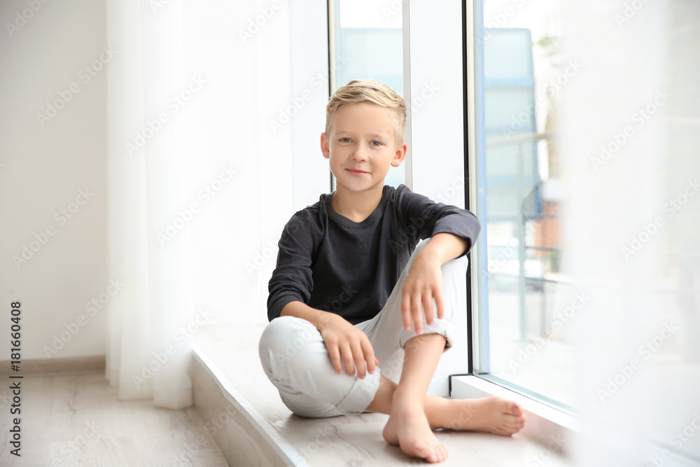 Cute little boy sitting near window at home Cute little boy sitting near window at home