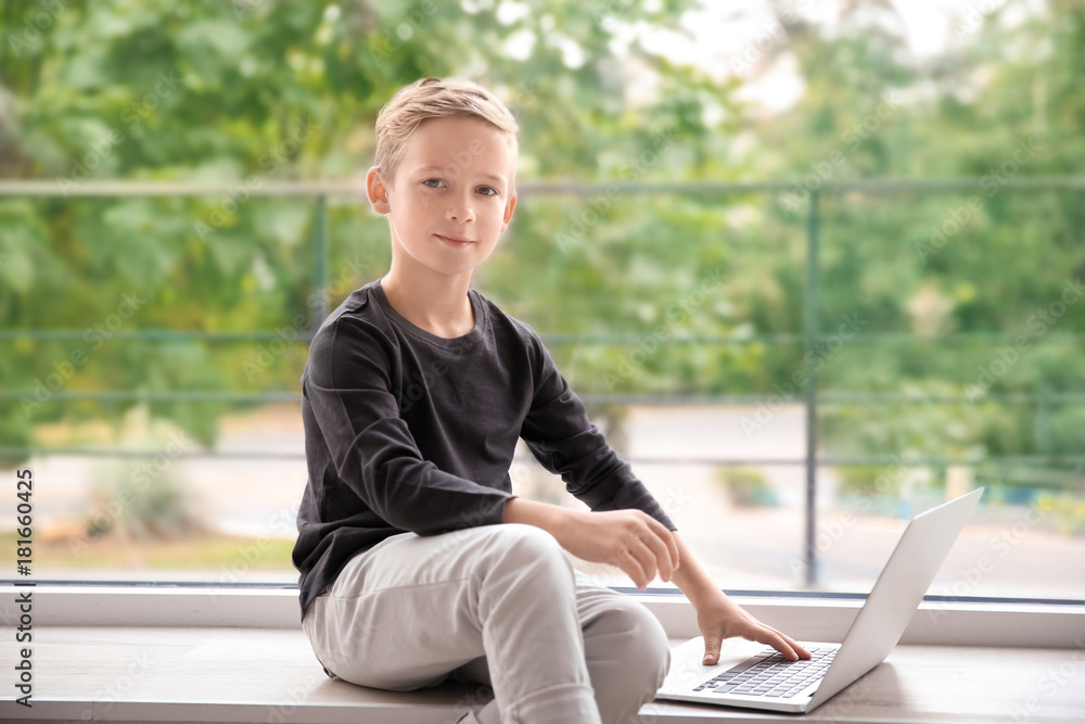 Obraz premium Cute little boy with laptop at home