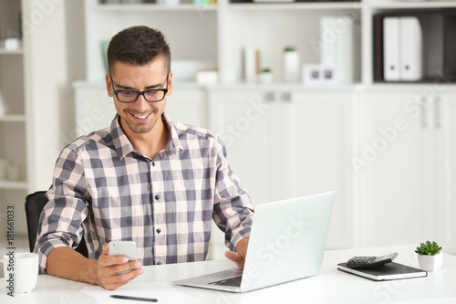 Attractive man with laptop and smartphone in office