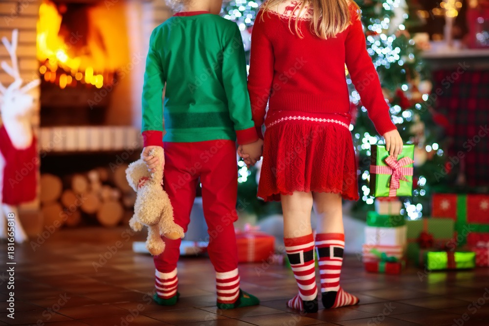 Obraz premium Child at Christmas tree. Kids at fireplace on Xmas