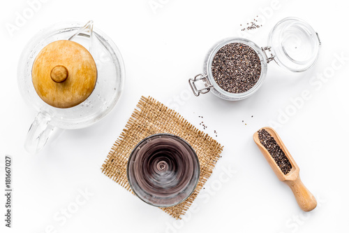 Brew chia seeds. Jar with seeds, scoop, bowl, tea pot with hot water. White background top view