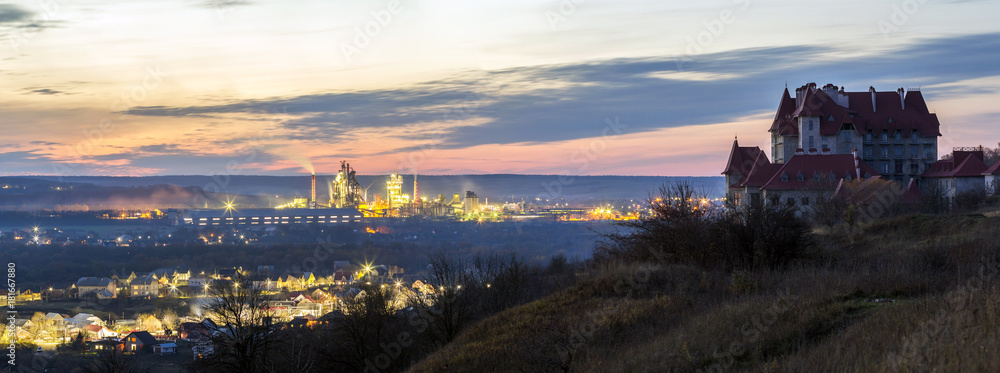 Naklejka premium Lonely building castle standing on top of mountain hill and industrial power station oland behind at night. Ivano-Frankivsk city, Ukraine.