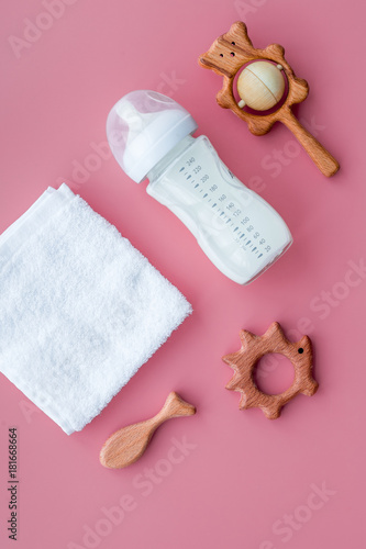 Little baby background. Wooden toys, pacifier, bottle, towel on pink background top view