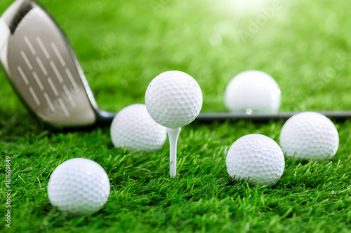Golf balls and golf club on green grass