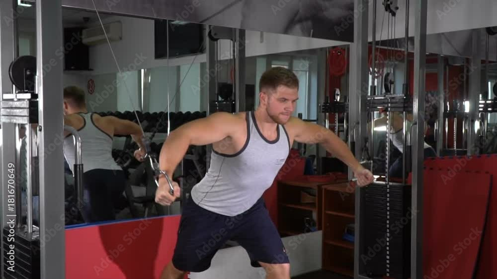 Male athlete trains on the simulator in the gym. Slow motion Male athlete trains on the simulator in the gym. Slow motion