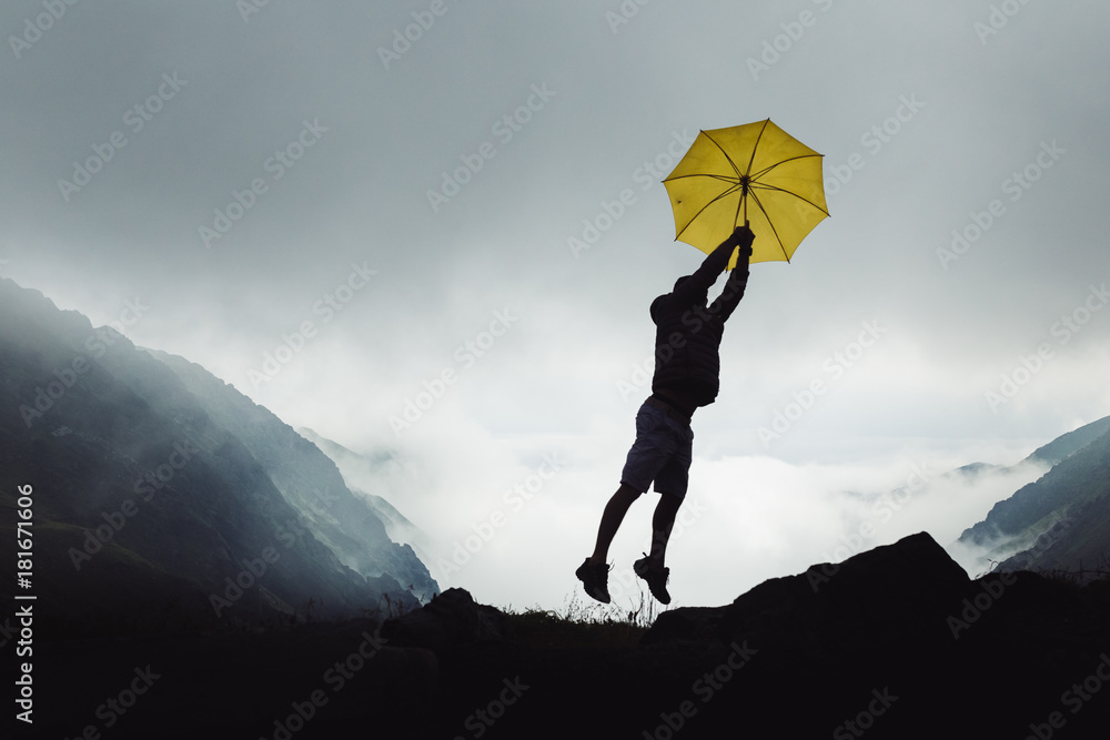 Obraz premium Man in the mountains, with a yellow umbrella