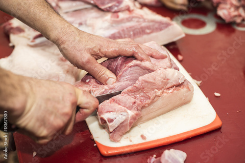 Man slicing pork meat on a table, working process closeup