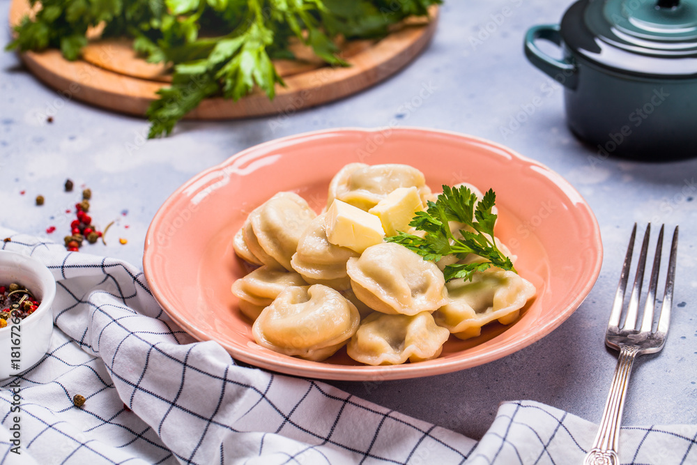 Boiled dumplings in a gray plate on a gray background, parsley, horizontal Boiled dumplings in a gray plate on a gray background, parsley, horizontal