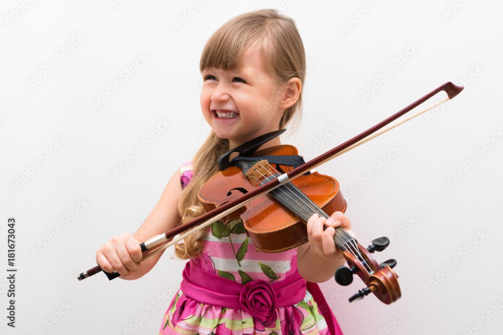 Cute little girl in a beautiful dress playing violin. Joyful and happy ...