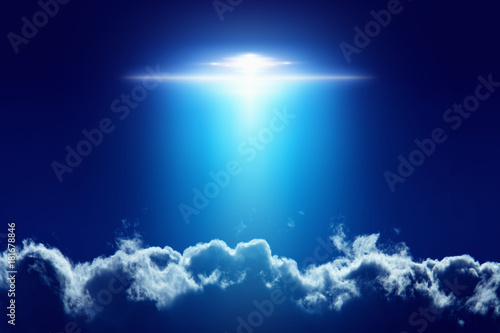 Extraterrestrial aliens spaceship, ufo with bright spotlight in dark blue sky