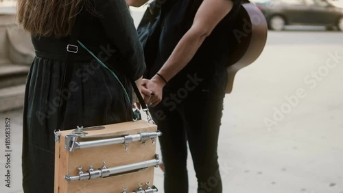 Young beautiful couple standing in downtown and hugging. Woman with sketchbox holding hands of man with guitar. photo