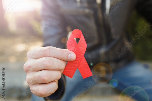 red aids ribbon in hand on green background, HIV photo