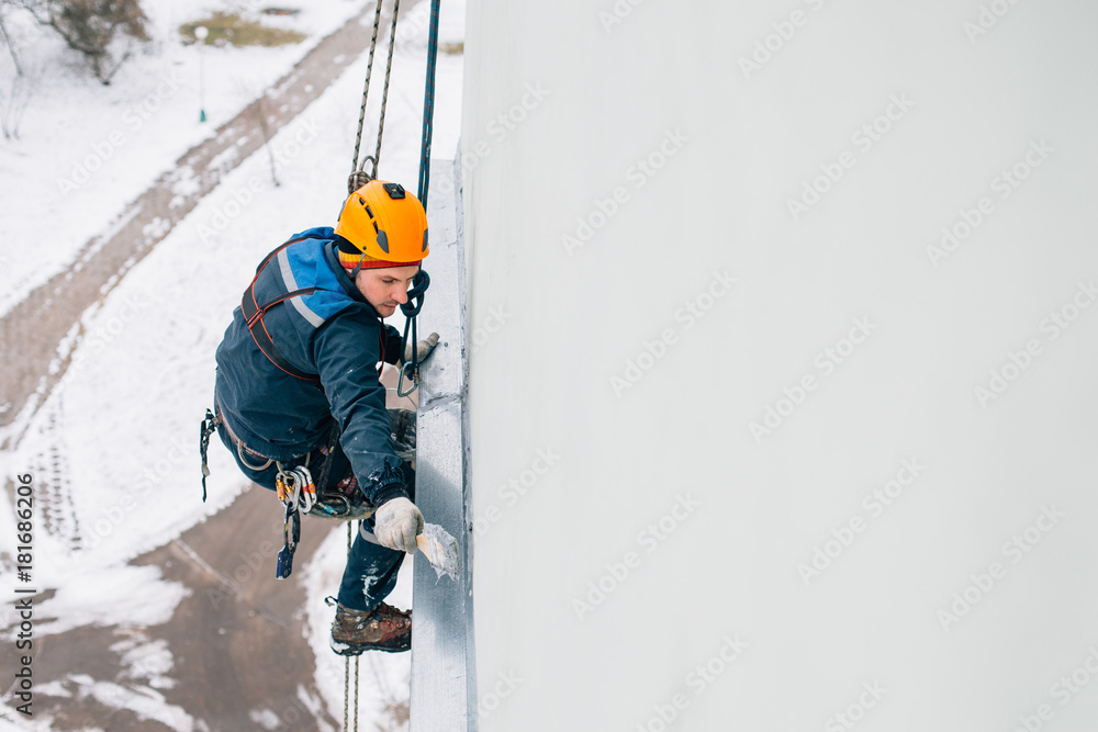 Professional industrial climber in helmet and uniform works at height. Risky extreme job.