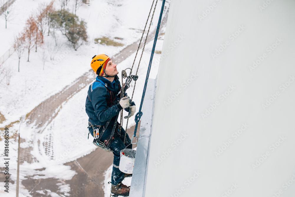 Professional industrial climber in helmet and uniform works at height. Risky extreme job.
