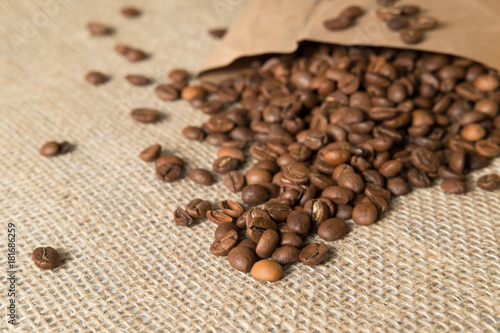 coffee beans spilled out of a paper bag on a linen surface bag