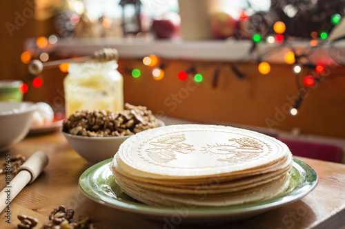 Christmas wafers placed on a wooden kitchen table  on a green plate next to a window. Wafers are round  cream color  surrounded by ingredients