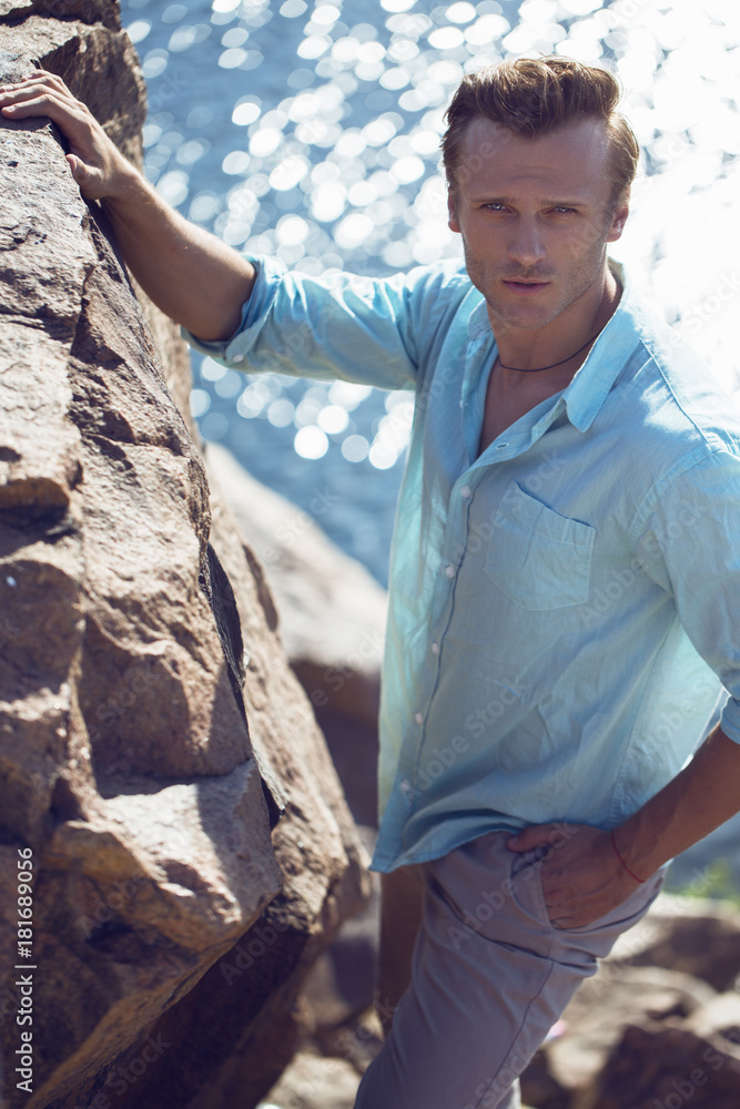 Portrait of a young and handsome man in a aqua shirt and light