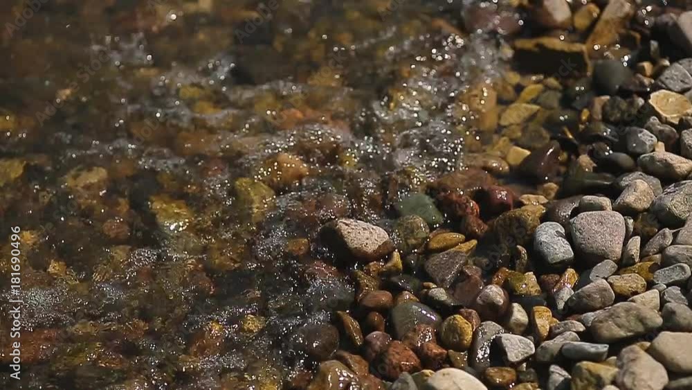 Pebble beach with small pebbles and sea surf. The surface of the sea on a wild pebble beach. The waves are to the camera. The view under water. Pebble beach with small pebbles and sea surf. The surface of the sea on a wild pebble beach. The waves are to the camera. The view under water.