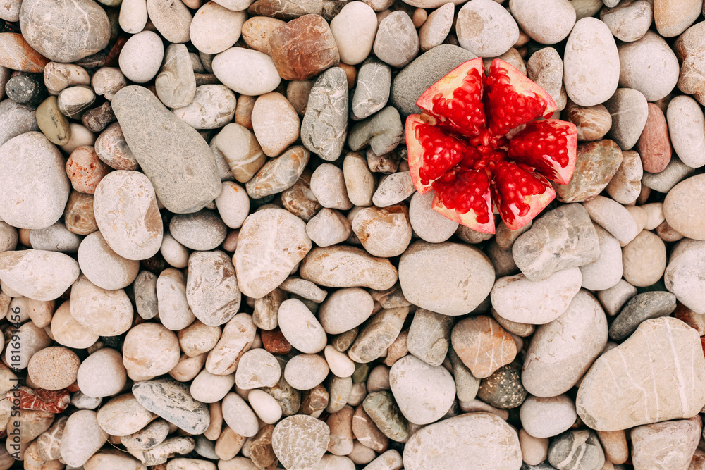 Pomegranate on a stony beach Background, close-up top view Pomegranate on a stony beach Background, close-up top view