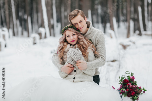 Newlyweds are hugging in the winter forest. Couple in love. Winter wedding ceremony.