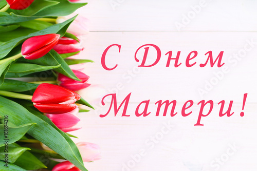 Pink tulips on a white wooden table with an inscription in Russian - Happy Mother's Day.