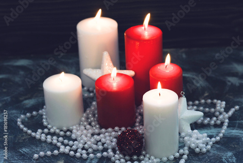 Red and white candles baubles and beads on a dark wooden background