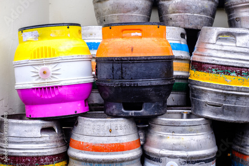 A number of metal beer barrels of various colors.