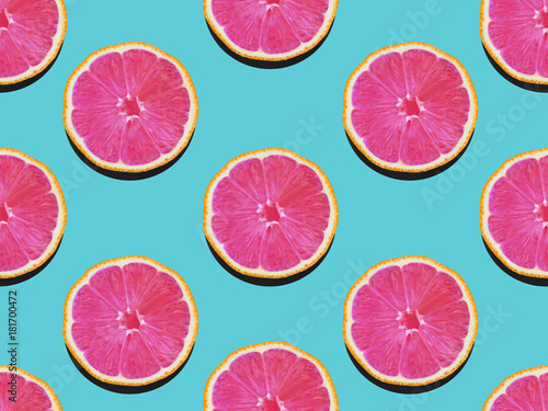 Grapefruit in flat lay Fruity pattern of grapefruit with pink flesh on a turquoise background Top view Modern flat lay photo pattern in pop art style
