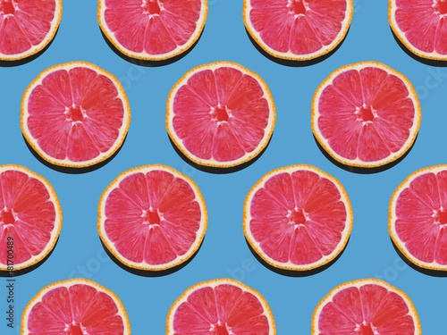 Grapefruit in flat lay Fruity pattern of grapefruit with red flesh on a blue background Top view Modern flat lay photo pattern in pop art style
