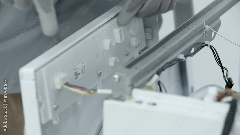 Repairman removing the plastic front side panel of the washing machine. Then he carefully unplugs the electric cabels. Repairman removing the plastic front side panel of the washing machine. Then he carefully unplugs the electric cabels.