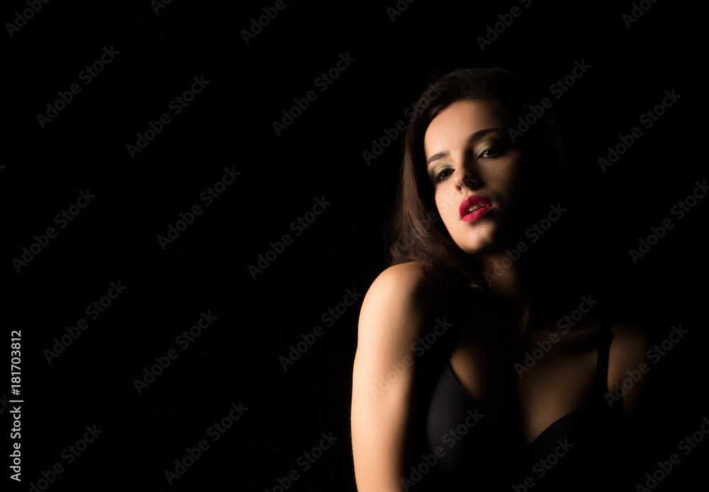 Closeup portrait of seductive woman with bright makeup posing with naked shoulders in the dark Closeup portrait of seductive woman with bright makeup posing with naked shoulders in the dark
