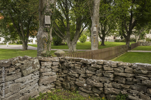 A view over a park with a stone wall and bat nest boxes on trees