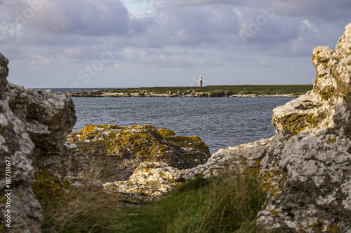 A lime stone rocky coast with a light house in the background in the southern part of Gotland 
