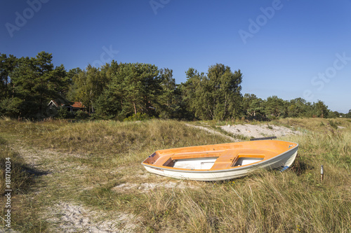 A white and orange boat left on a sandy beach © Pawel Sidlo