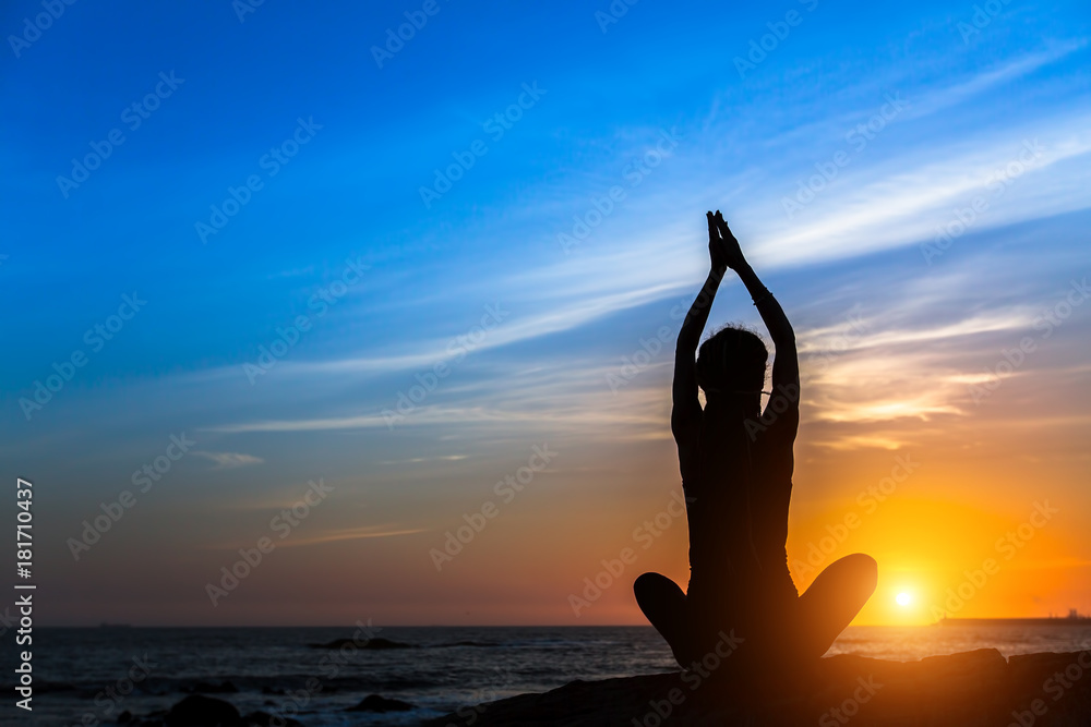 Yoga meditation woman on the ocean during amazing sunset.