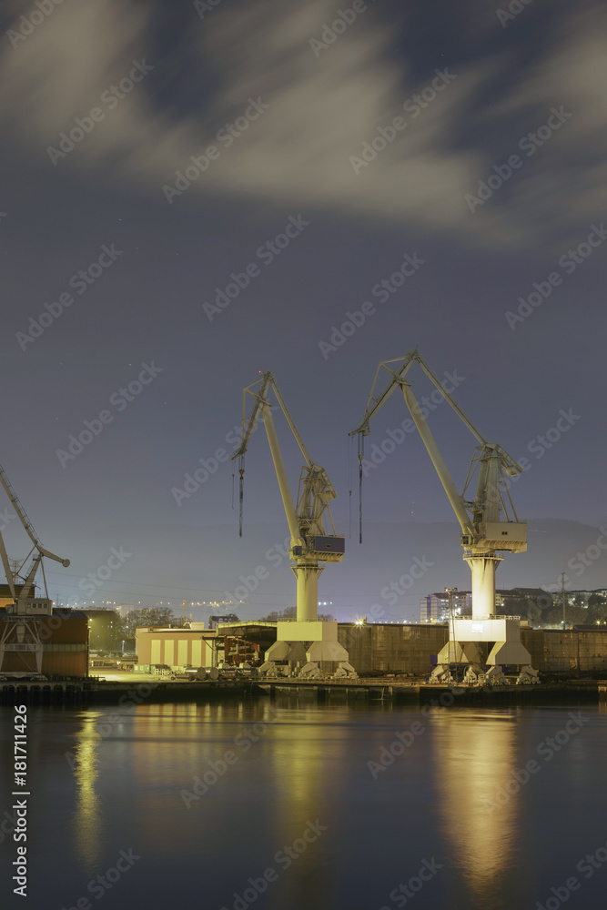 Monumental Cranes at sunrise in Shipyard. Night activity at the naval factories surrounding the city of Bilbao, Spain.