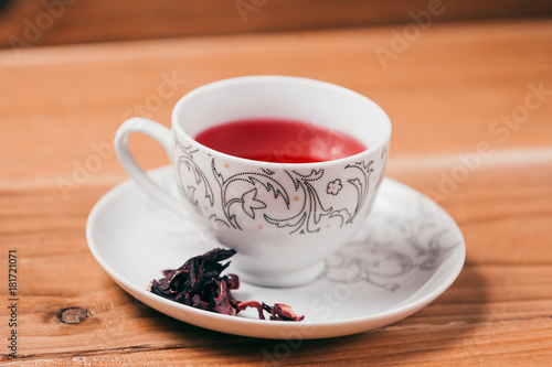 Red hot hibiscus tea in a glass mug on a wooden table