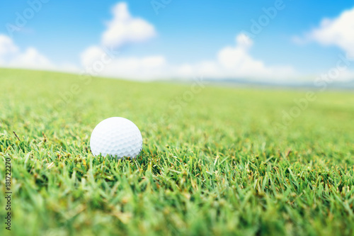 Golf ball on the grass and sky background.