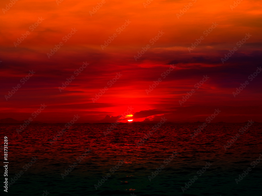 sunset last light of sun on horizontal line over red sky and ocean