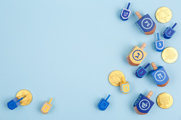 Blue background with multicolor dreidels and chocolate coins. Hanukkah and judaic holiday concept.